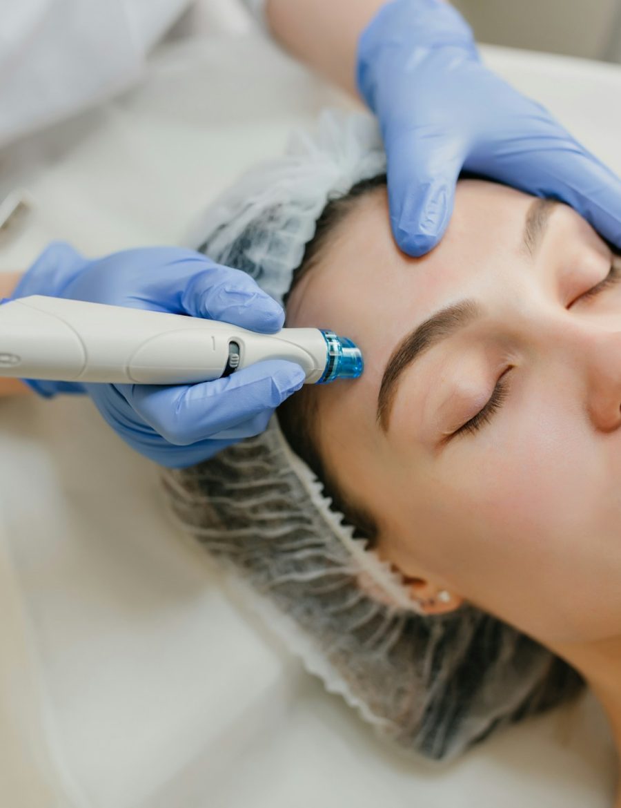 A practitioner working across a patient's forehead with a skin-resurfacing handpiece