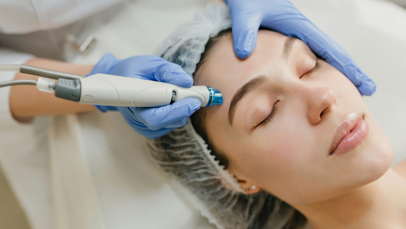 A practitioner working across a patient's forehead with a skin-resurfacing handpiece